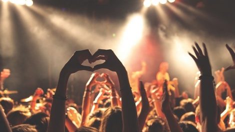 People in a crowd holding their arms up and watching a concert put on by one of many bands from Colorado