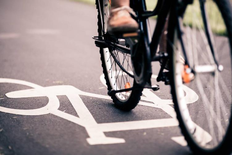 The wheels of a bicycle and a bicycle sign on a street