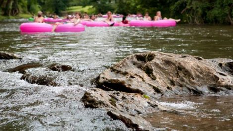 A group of people in pink rafts river tubing in Colorado