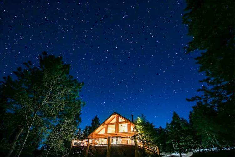 A secluded cabin in Colorado lit up at night under a starry night sky